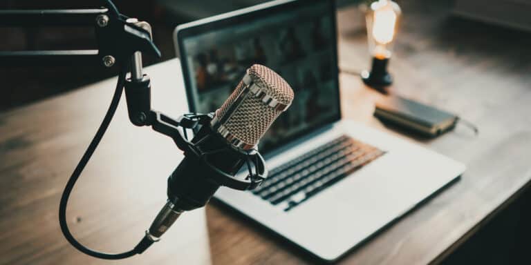 Home studio podcast interior. Microphone, laptop and on air lamp on the table, close-up