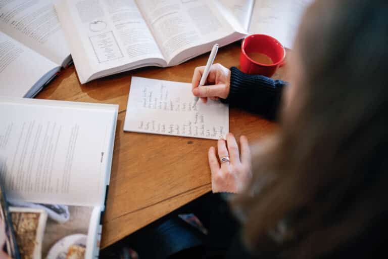 over the shoulder view of woman handwriting her shopping list