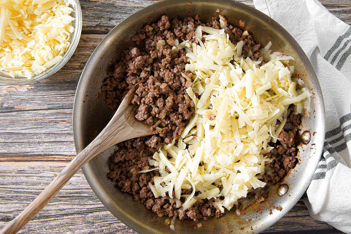 overhead view of beef and cheese for egg roll filling in a skillet