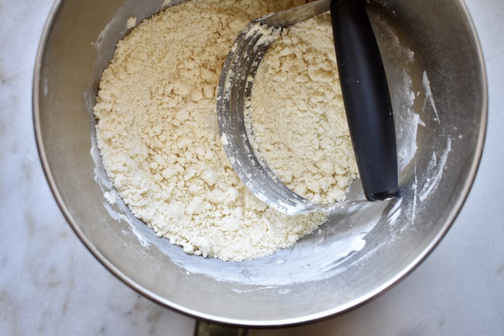 overhead shot of dry ingredients in metal bowl with pastry cutter
