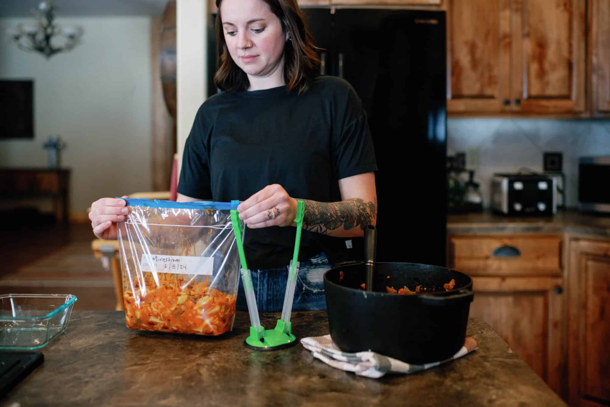 woman closing ziploc bag of soup for freezing