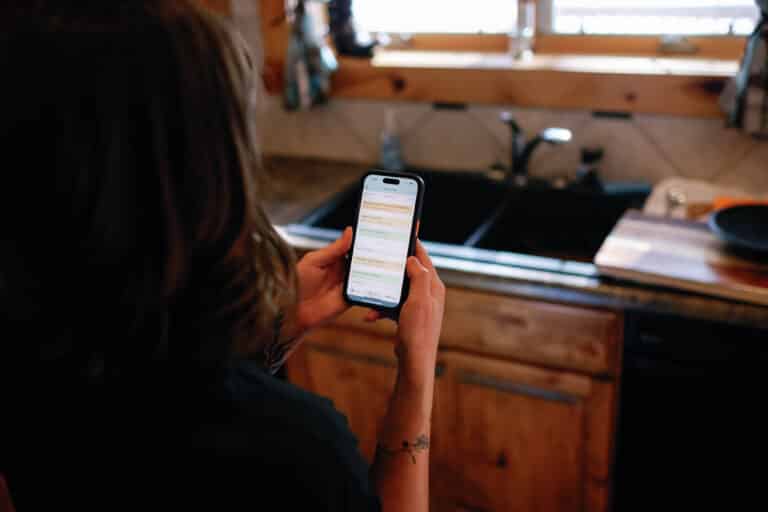 over the shoulder view of woman in a kitchen viewing Plan to Eat on her phone