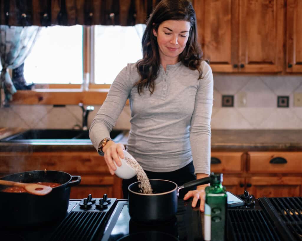 woman pouring quinoa into a pot in the stove