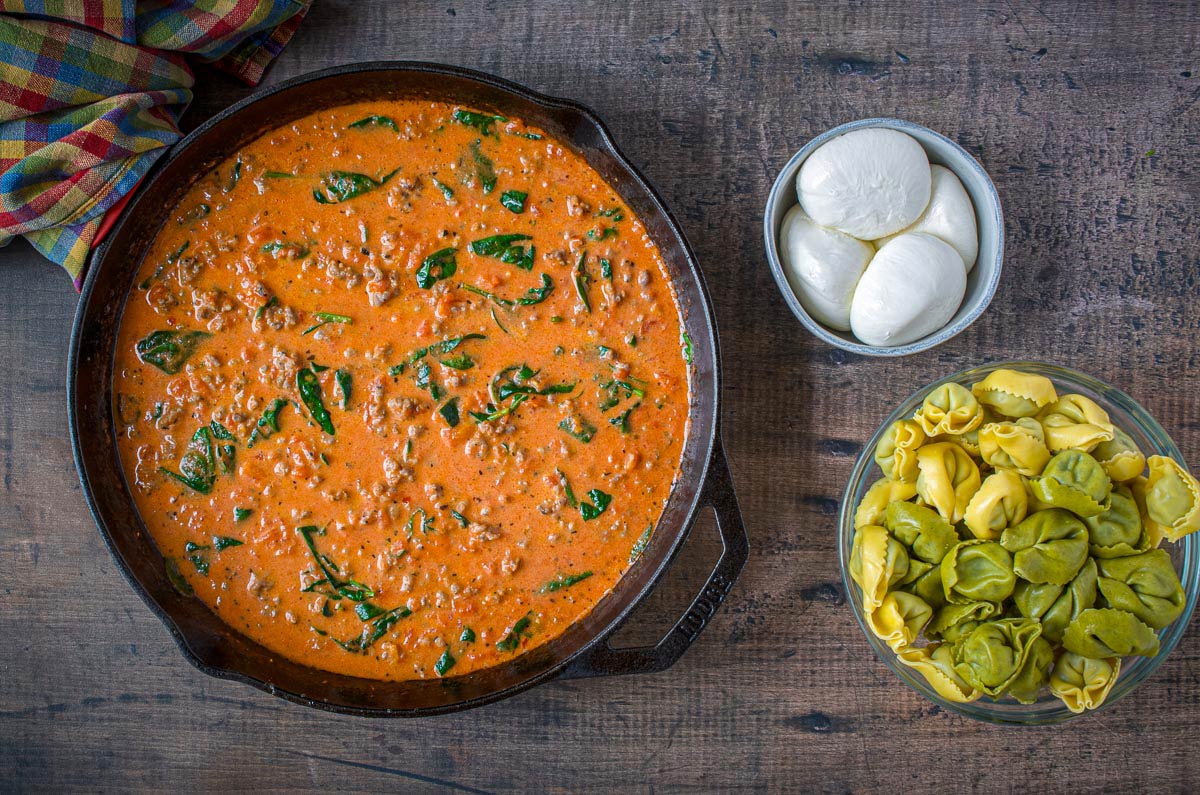 overhead view of homemade ragu sauce, burrata cheese, and tortellini